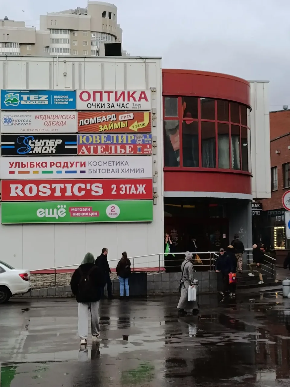 Вход в ТЦ «Депо Молл» на улице Яблочкова: на фасаде вывески магазинов, справа вход с крыльцом